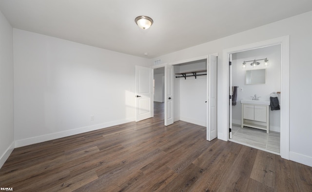 unfurnished bedroom with sink, connected bathroom, and dark hardwood / wood-style flooring