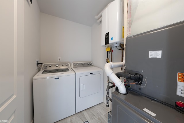 laundry room with heating unit, washing machine and clothes dryer, and water heater