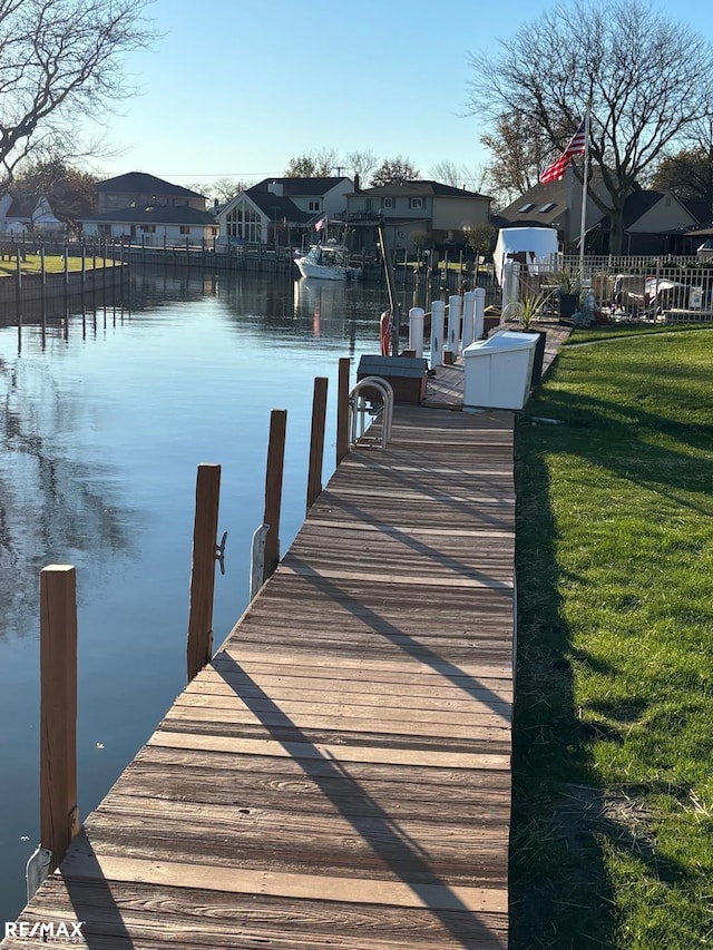 view of dock featuring a lawn and a water view