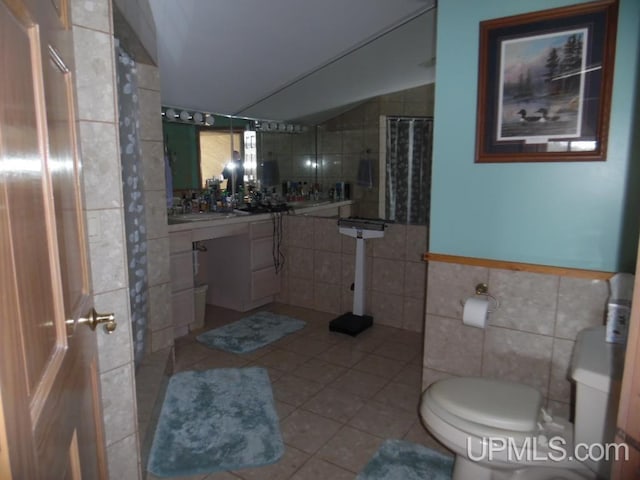 bathroom with toilet, a shower with curtain, vaulted ceiling, tile walls, and tile patterned flooring