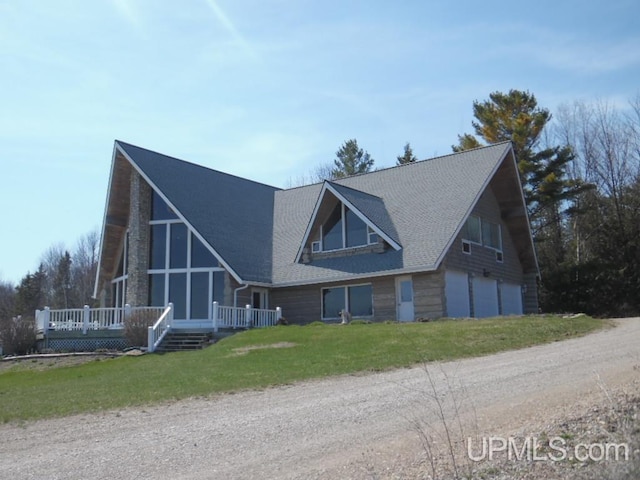 view of front of house featuring a wooden deck, a garage, and a front yard