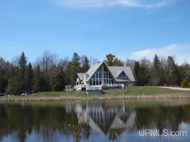 rear view of property with a water view and a yard