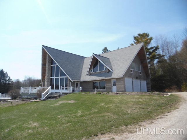 rear view of house featuring a garage and a lawn