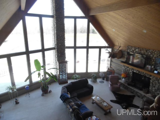 living room featuring beam ceiling, a stone fireplace, and high vaulted ceiling