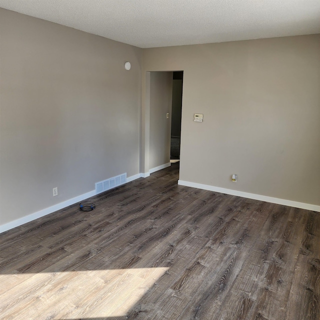 empty room featuring dark wood-type flooring and a textured ceiling