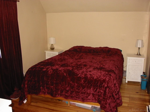 bedroom with hardwood / wood-style flooring and lofted ceiling