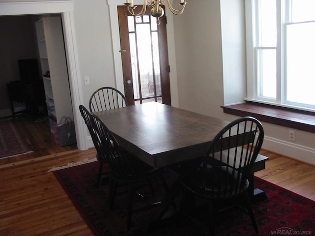 dining area with dark hardwood / wood-style floors and an inviting chandelier