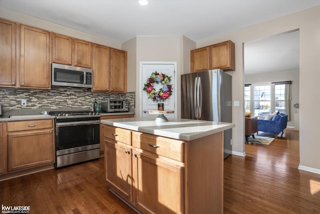 kitchen with dark wood-type flooring, stainless steel appliances, tasteful backsplash, light stone counters, and a kitchen island