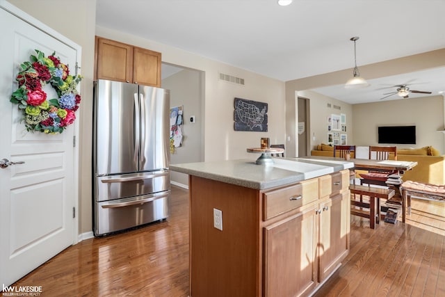 kitchen featuring pendant lighting, stainless steel fridge, ceiling fan, dark hardwood / wood-style floors, and a center island