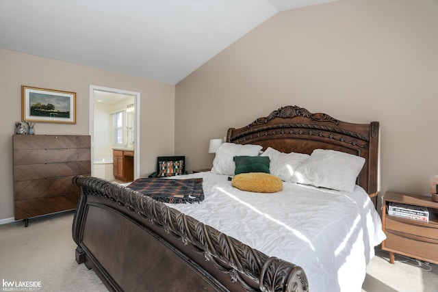 bedroom with ensuite bathroom, vaulted ceiling, and light carpet