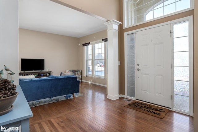 foyer entrance with a wealth of natural light, decorative columns, and dark hardwood / wood-style floors