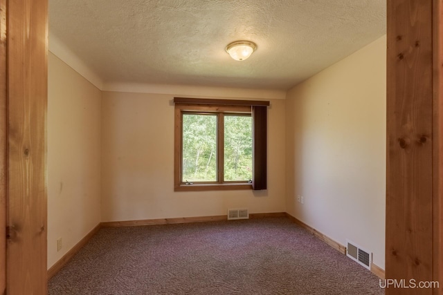 carpeted empty room featuring a textured ceiling