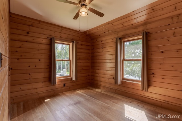 unfurnished room featuring wooden walls, light hardwood / wood-style floors, and ceiling fan