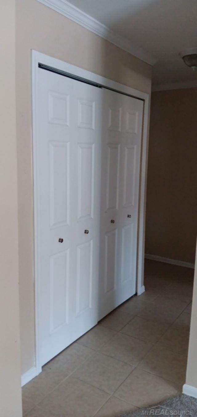 corridor featuring crown molding and light tile patterned floors