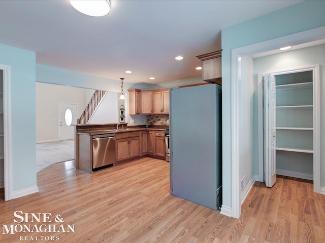 kitchen featuring pendant lighting, stainless steel appliances, tasteful backsplash, light hardwood / wood-style floors, and kitchen peninsula