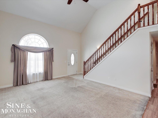 foyer with high vaulted ceiling, light colored carpet, and ceiling fan