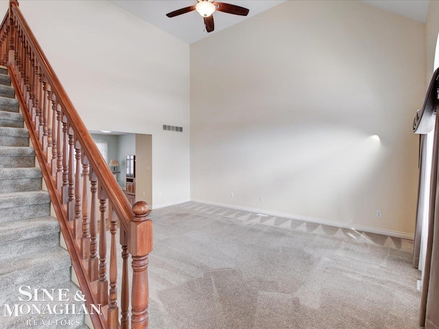 carpeted empty room with high vaulted ceiling and ceiling fan