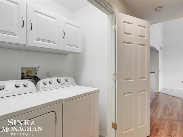 laundry area featuring cabinets, separate washer and dryer, and light hardwood / wood-style floors