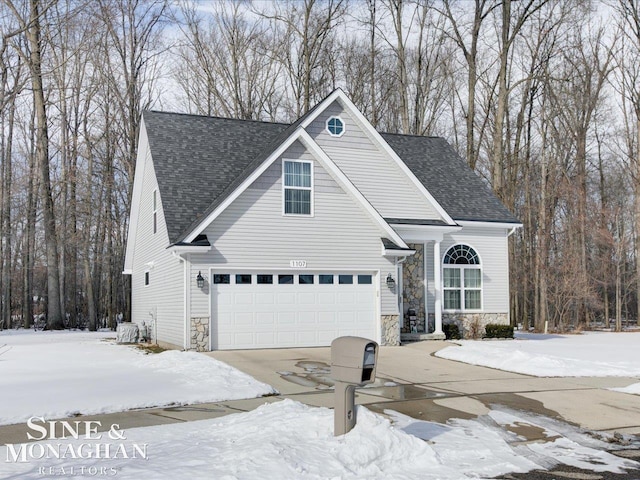 traditional home featuring concrete driveway, a garage, stone siding, and roof with shingles