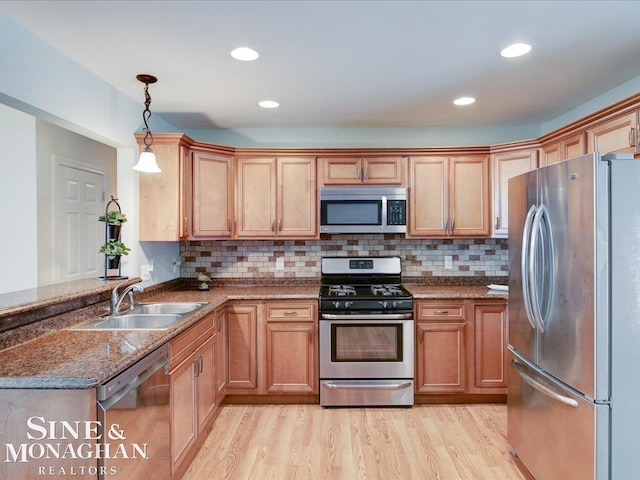 kitchen featuring decorative light fixtures, sink, backsplash, dark stone counters, and stainless steel appliances