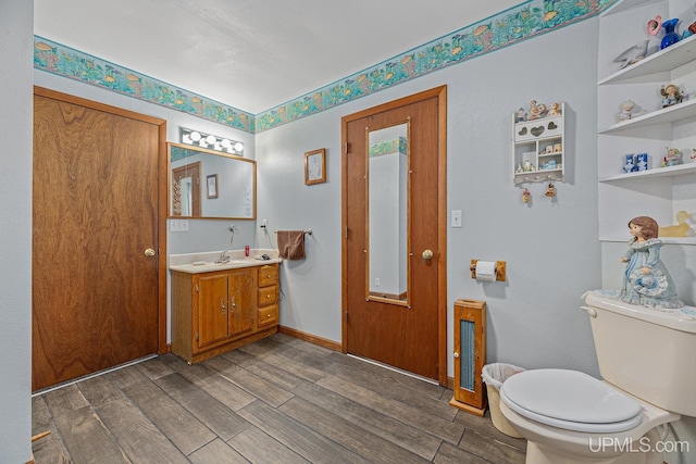 bathroom featuring wood-type flooring, toilet, and vanity