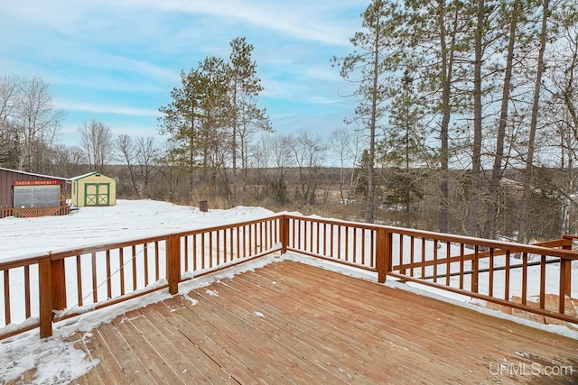 snow covered deck featuring a storage shed