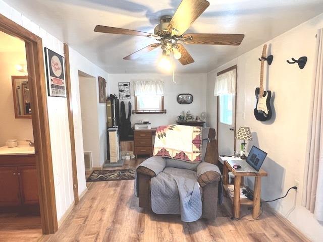 living area with hardwood / wood-style flooring, sink, and ceiling fan