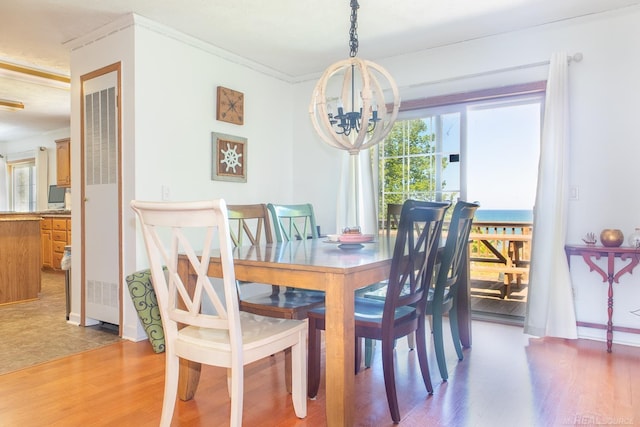 dining space with crown molding, plenty of natural light, wood-type flooring, and a notable chandelier