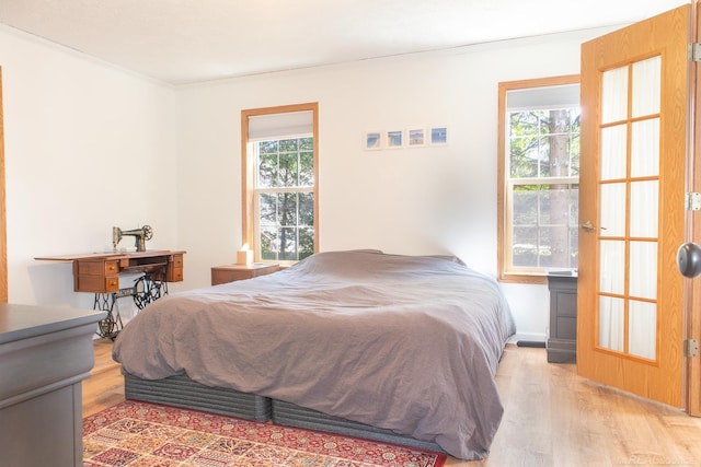 bedroom featuring multiple windows, hardwood / wood-style floors, and ornamental molding