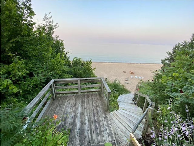 deck at dusk featuring a beach view and a water view