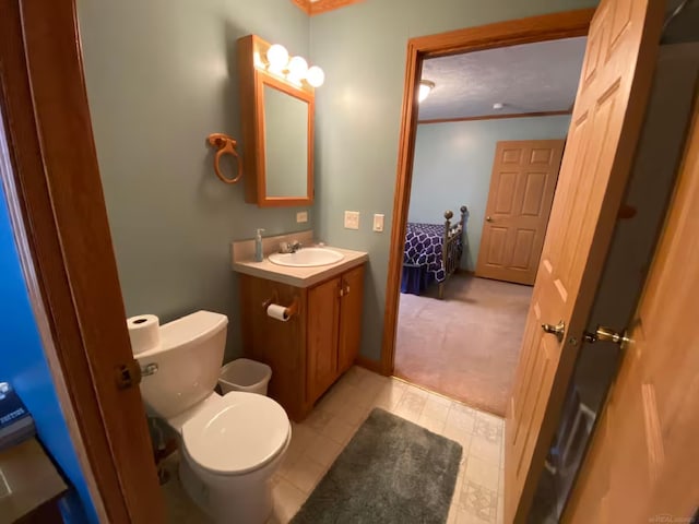 bathroom with ornamental molding, vanity, and toilet