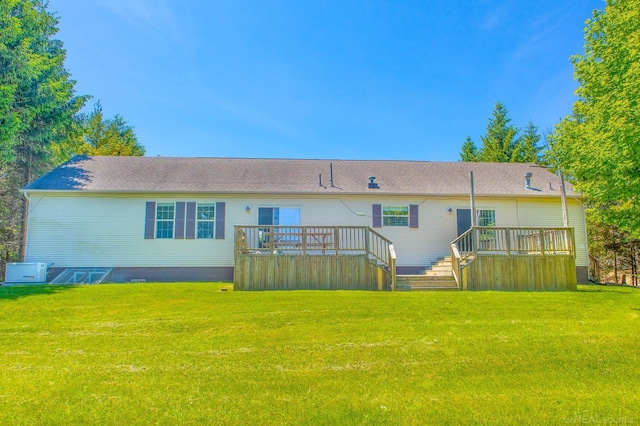 rear view of house with a wooden deck and a lawn