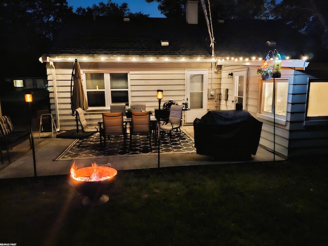 back house at twilight with a patio and a fire pit