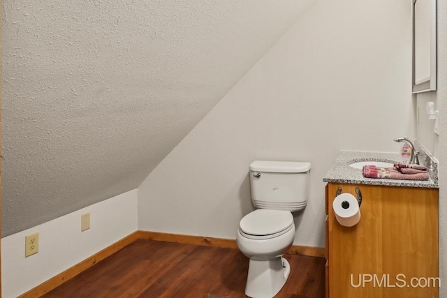 bathroom featuring hardwood / wood-style flooring, vanity, toilet, and vaulted ceiling