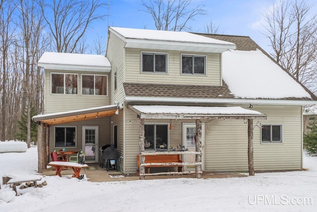 snow covered rear of property featuring covered porch