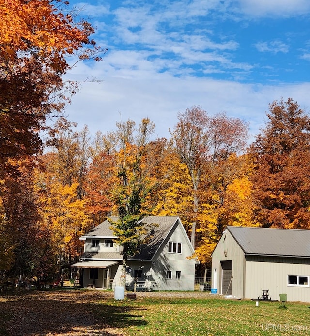 rear view of house featuring a garage, an outbuilding, and a lawn