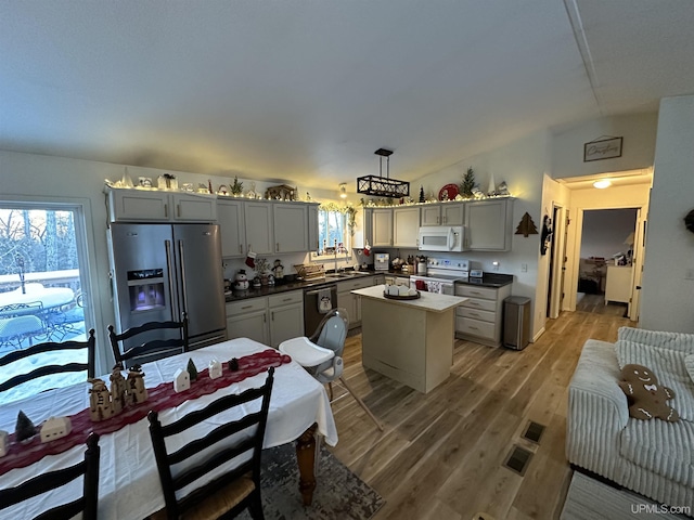 kitchen with white appliances, decorative light fixtures, a center island, and gray cabinetry