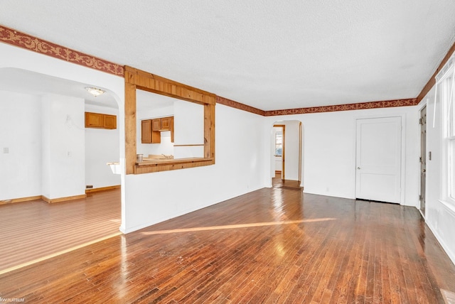 unfurnished living room with wood-type flooring and a textured ceiling