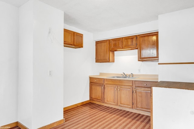 kitchen featuring sink, light hardwood / wood-style floors, and a textured ceiling