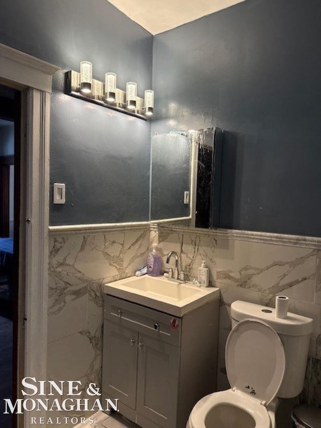 bathroom featuring vanity, tile walls, and toilet