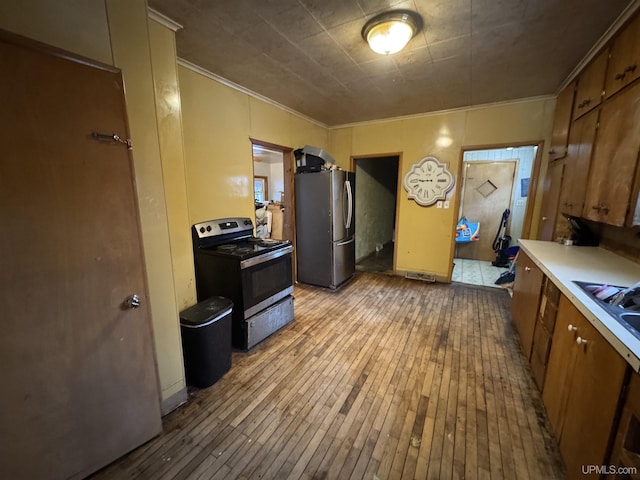 kitchen featuring sink, crown molding, stainless steel appliances, and light hardwood / wood-style floors