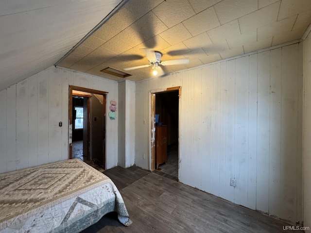 bedroom with dark wood-type flooring, vaulted ceiling, wooden walls, and ceiling fan