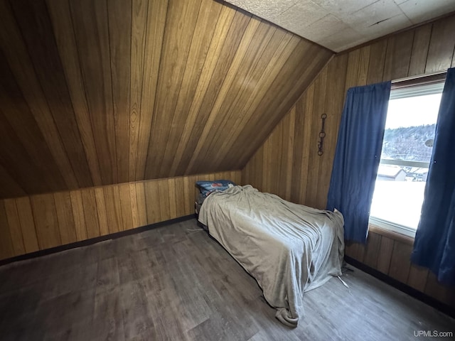 unfurnished bedroom featuring dark hardwood / wood-style flooring, vaulted ceiling, and wooden walls