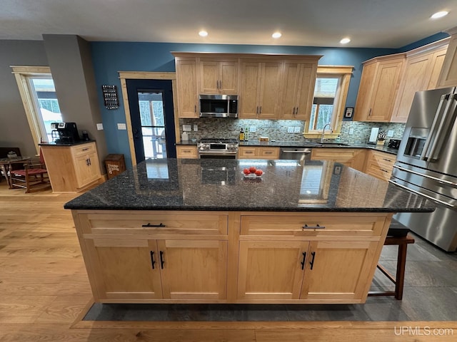 kitchen with plenty of natural light, stainless steel appliances, a kitchen island, and dark stone counters