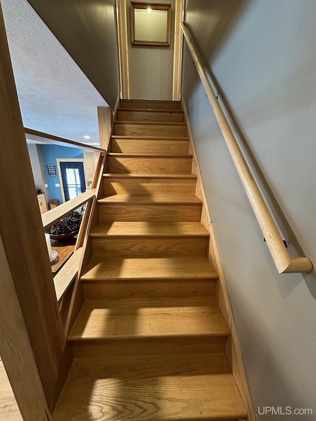 stairs featuring hardwood / wood-style floors, vaulted ceiling, and a textured ceiling