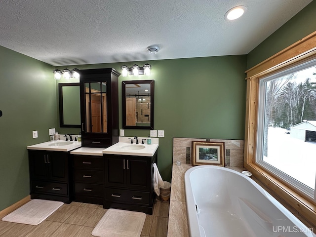 bathroom with vanity, a bath, tile patterned floors, and a textured ceiling