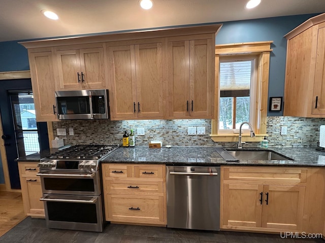 kitchen featuring tasteful backsplash, sink, dark stone countertops, and appliances with stainless steel finishes