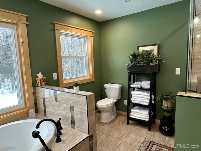 bathroom featuring a tub to relax in, toilet, and tile patterned flooring