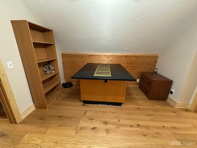 bonus room with lofted ceiling, light hardwood / wood-style floors, and wood walls