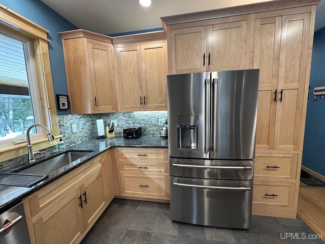 kitchen with stainless steel appliances, sink, decorative backsplash, and dark stone counters